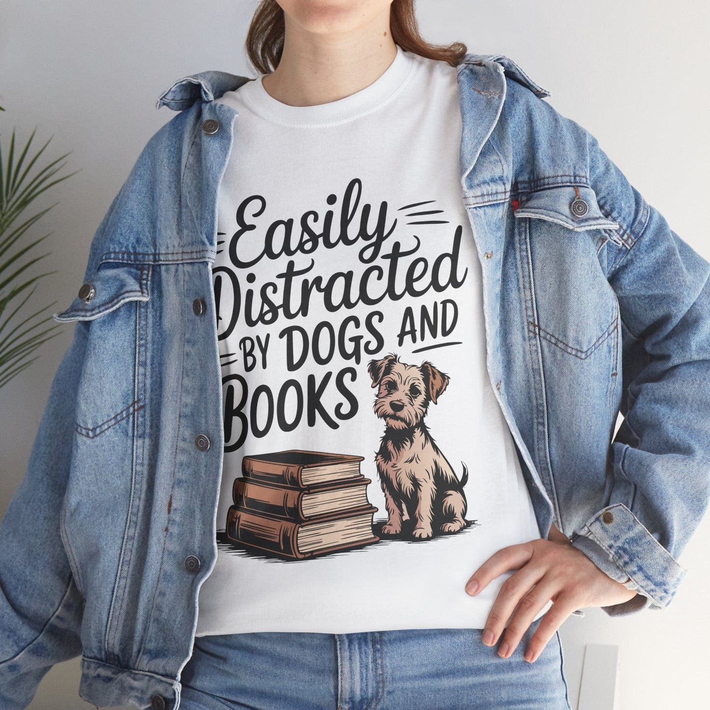 Person wearing a white t-shirt with a dog and book graphic and text 'Easily Distracted By Dogs And Books'.
