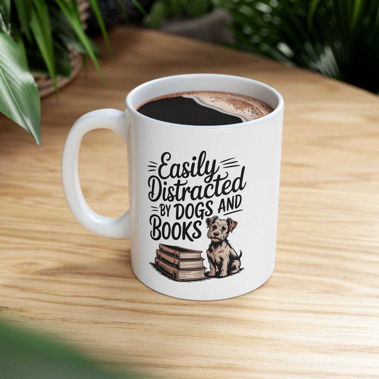 White mug with a dog and book design and text 'Easily Distracted by Dogs and Books' on a wooden surface.