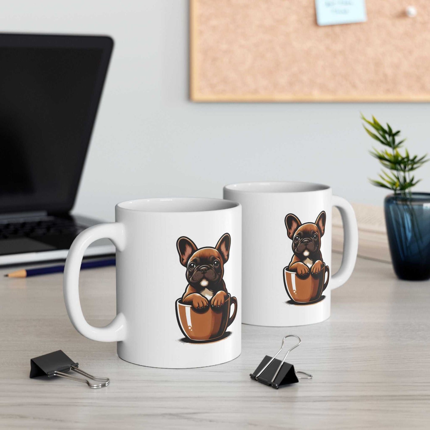 Two white mugs with dog illustrations on a desk with office supplies.