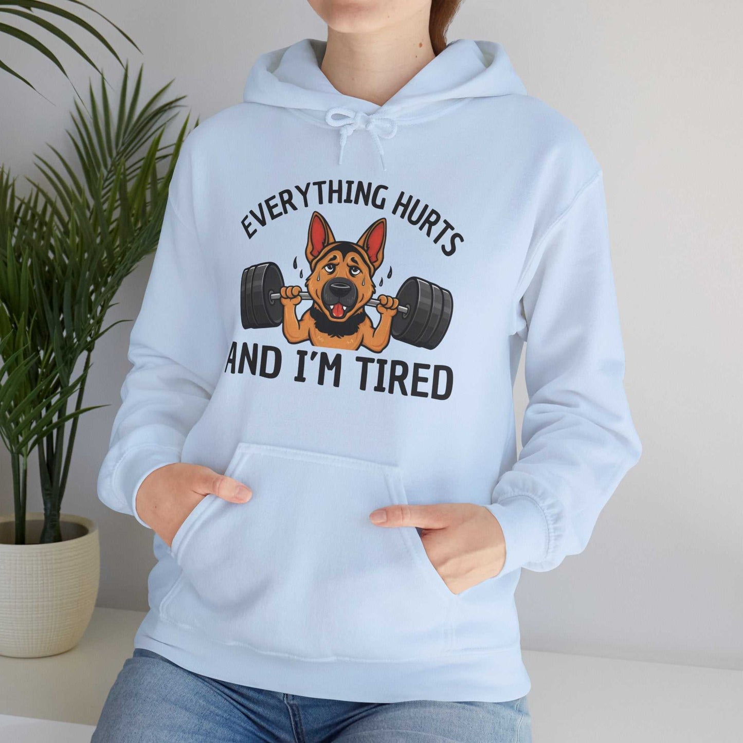 Light blue hoodie with a graphic of a dog lifting weights and text 'Everything hurts and I'm tired'.