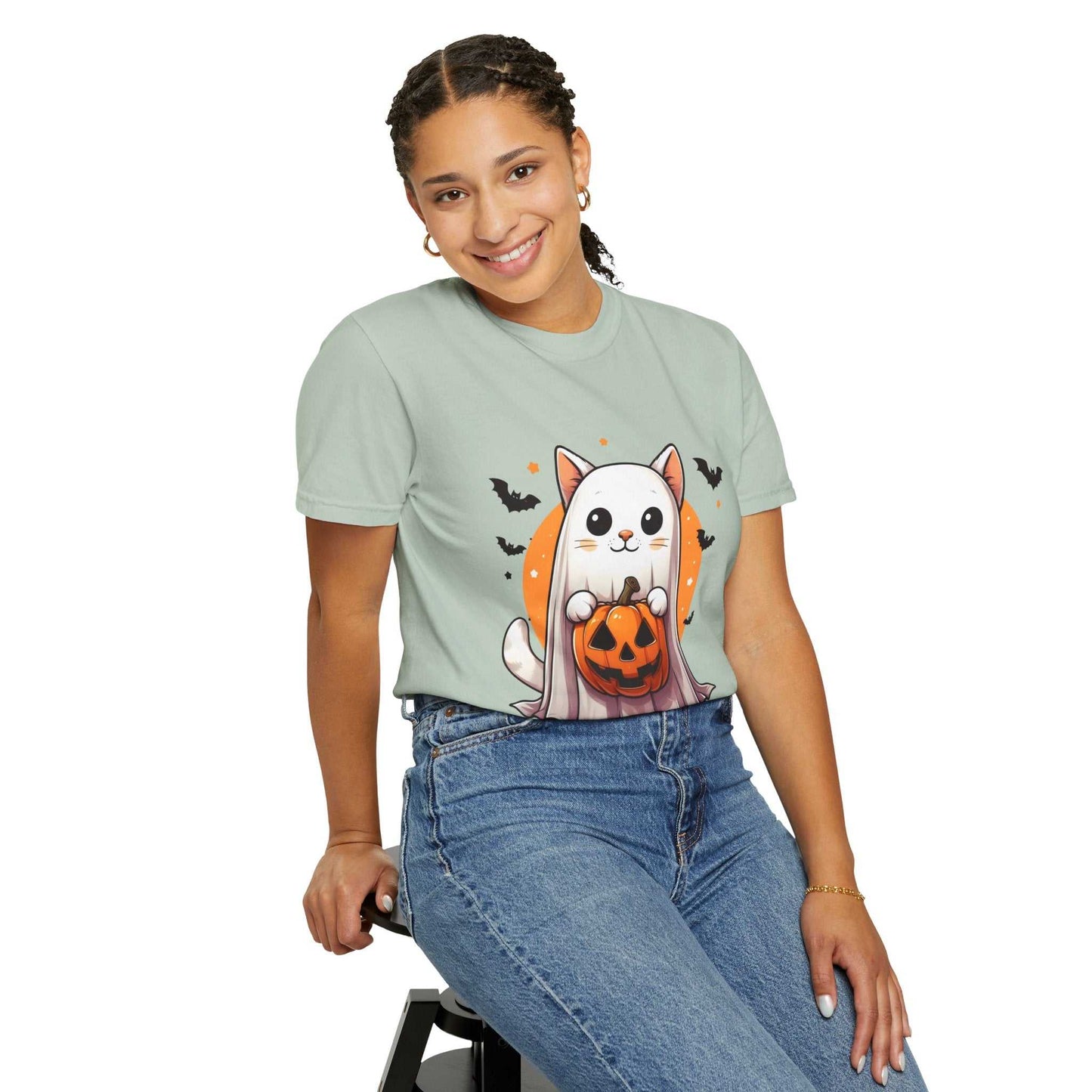 Person wearing a light green t-shirt with a cat and pumpkin design on a white background