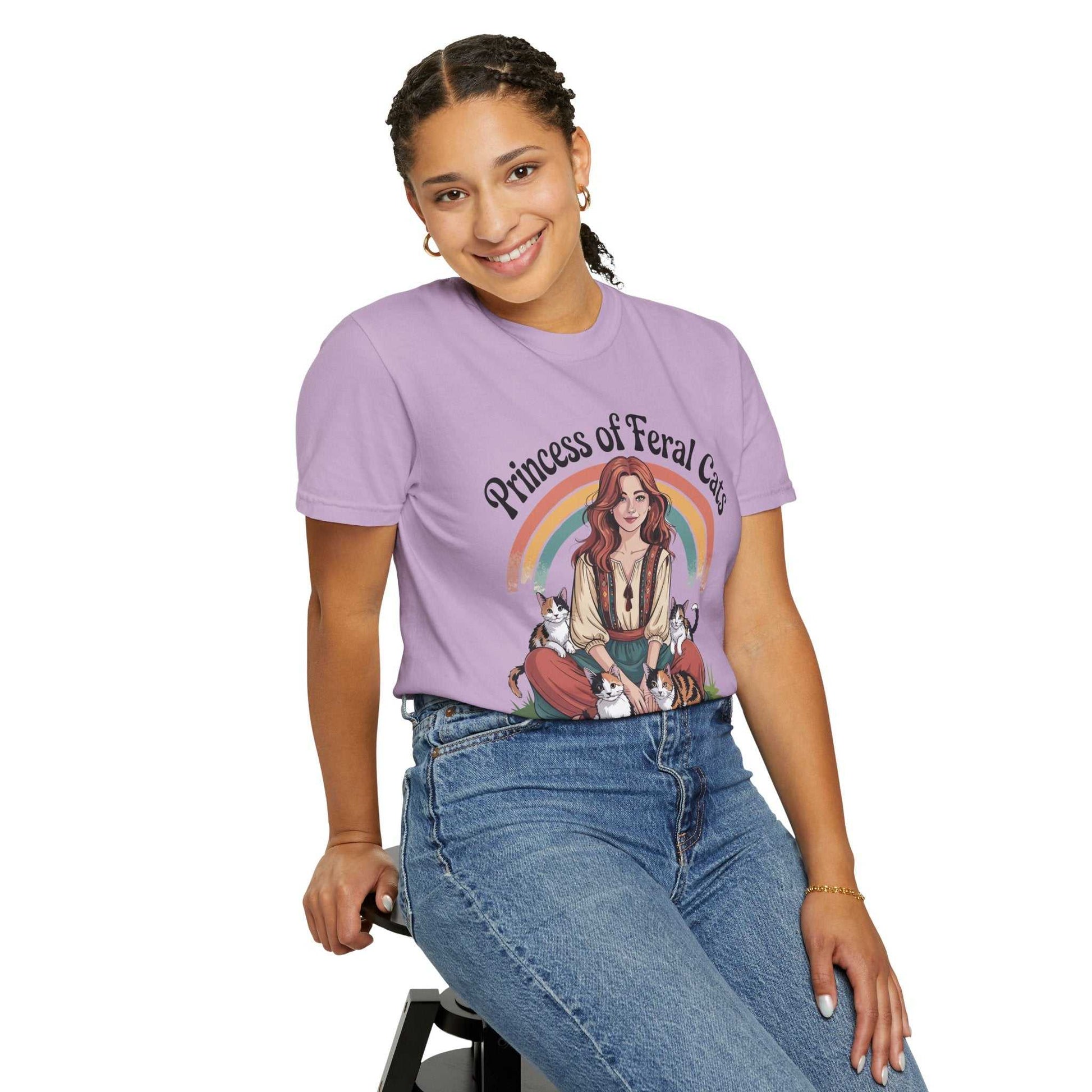 Person wearing a purple t-shirt with a graphic design and text, sitting on a stool against a white background.