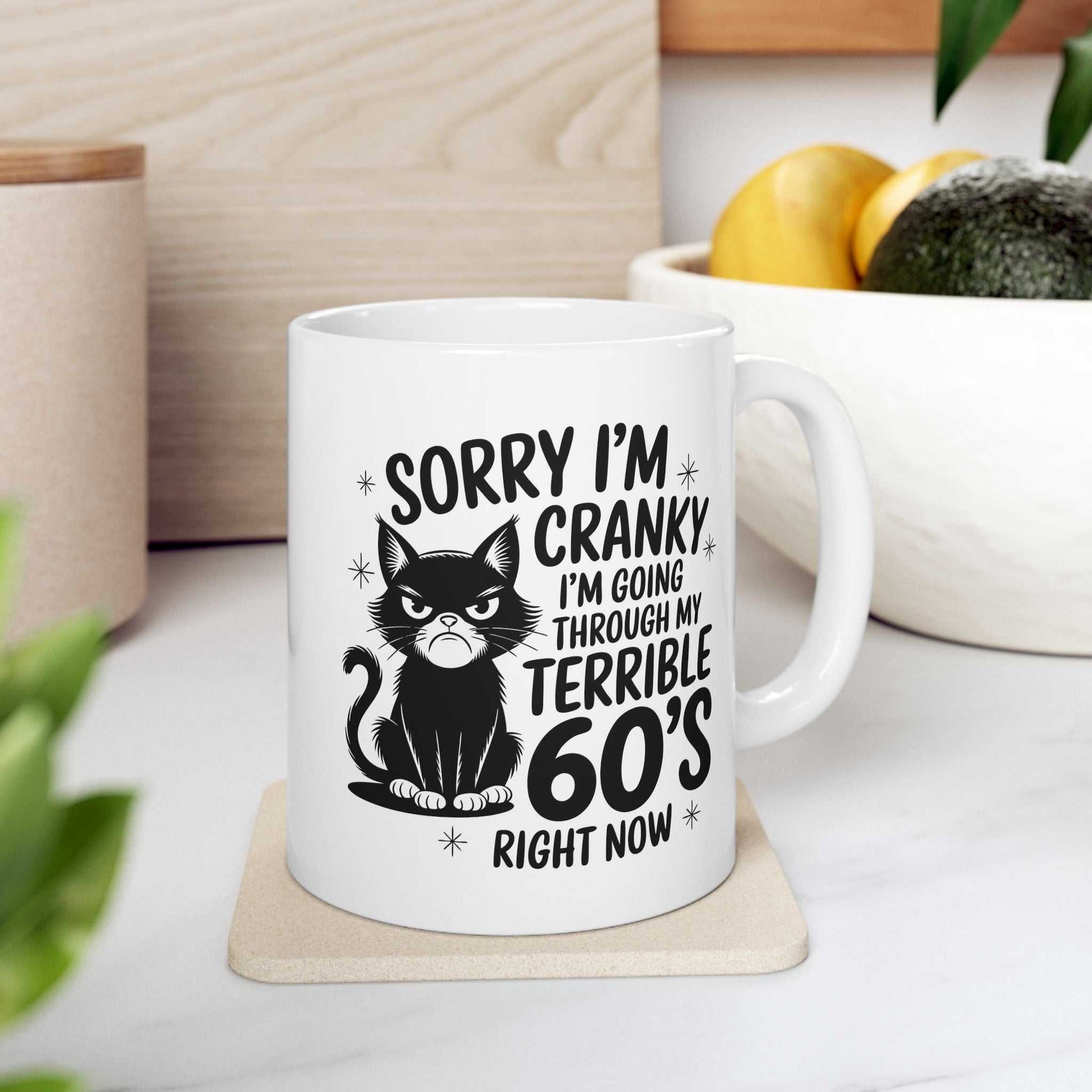 White mug with a black cat graphic and humorous text on a white surface.