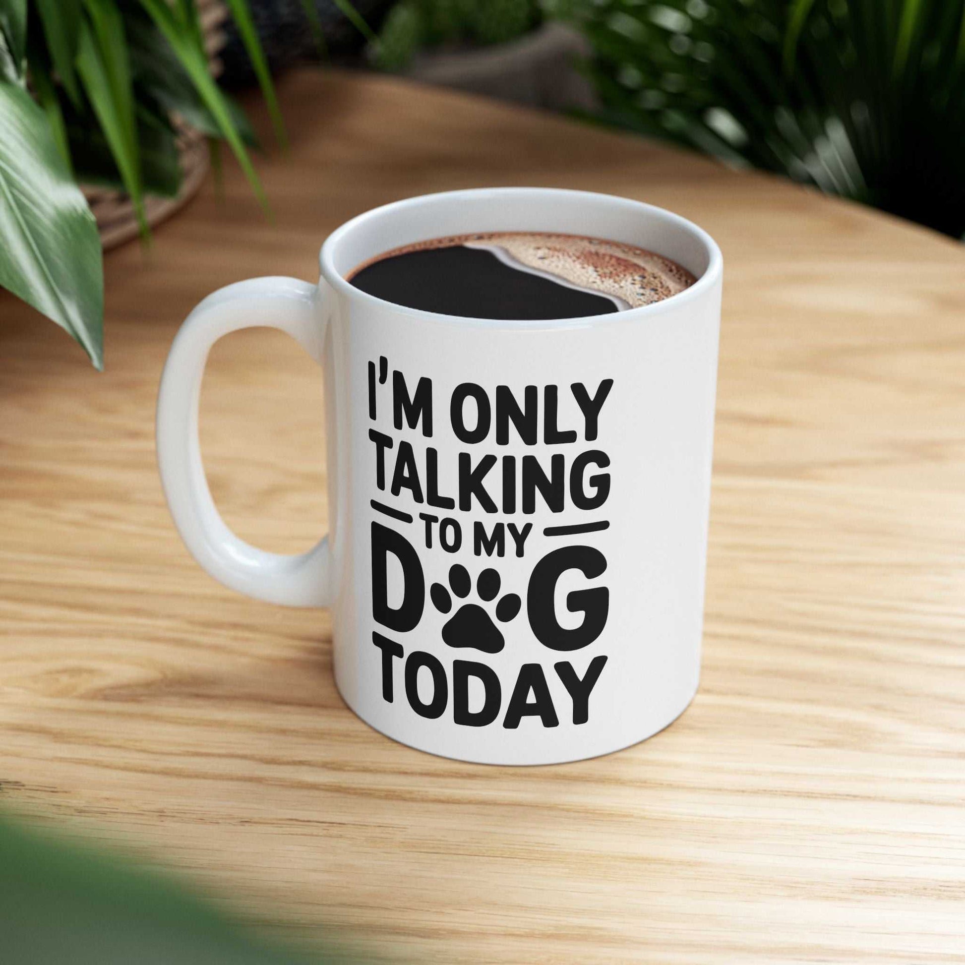 White mug with text 'I'm only talking to my dog today' on a wooden table.