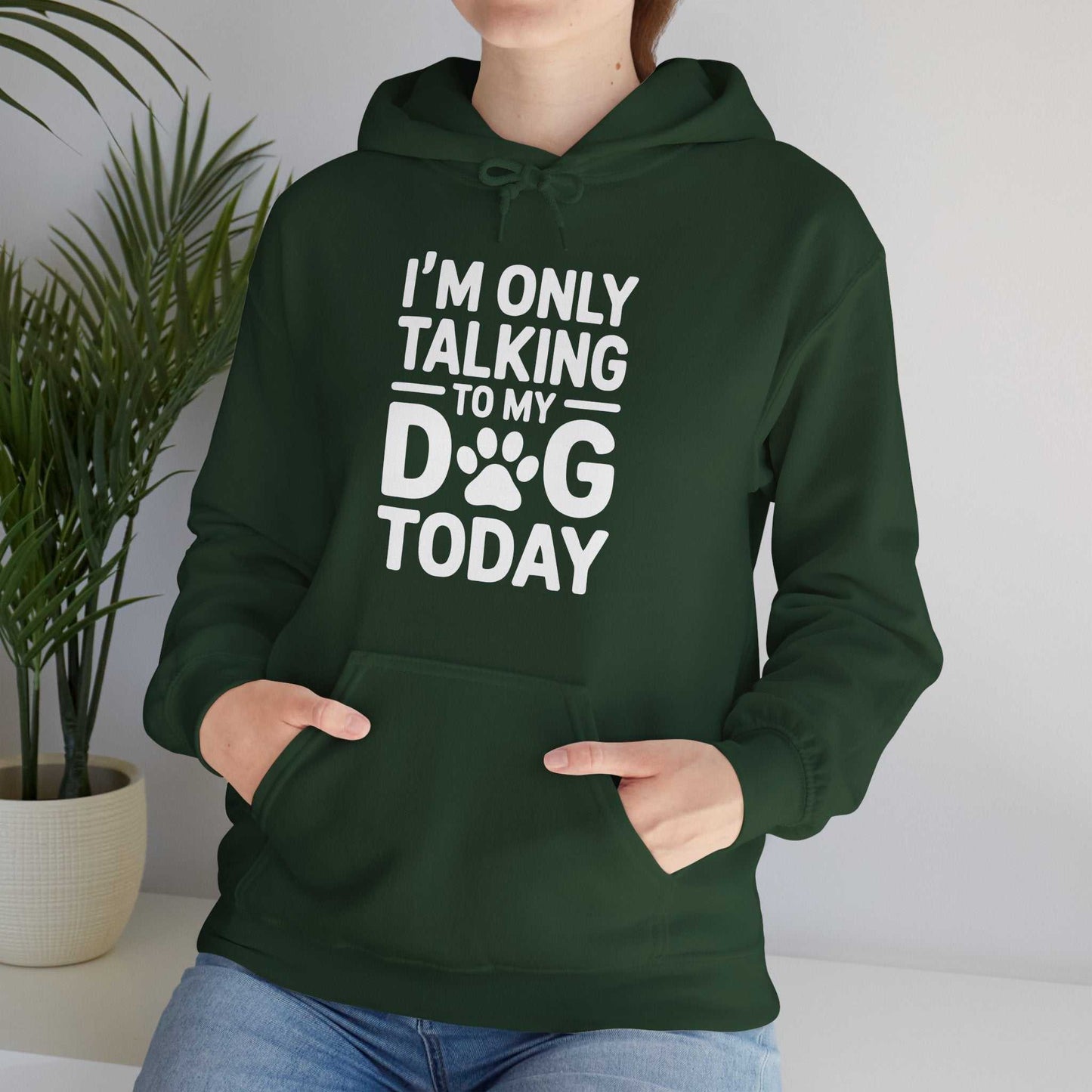 Person wearing a green hoodie with text and paw print design, sitting indoors.