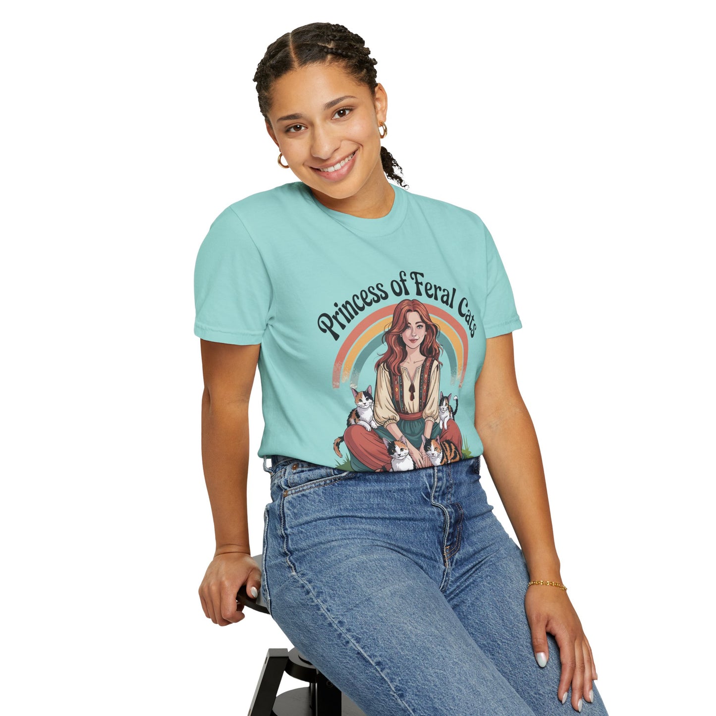 Person wearing a light blue t-shirt with a graphic design and text, sitting on a stool against a white background.