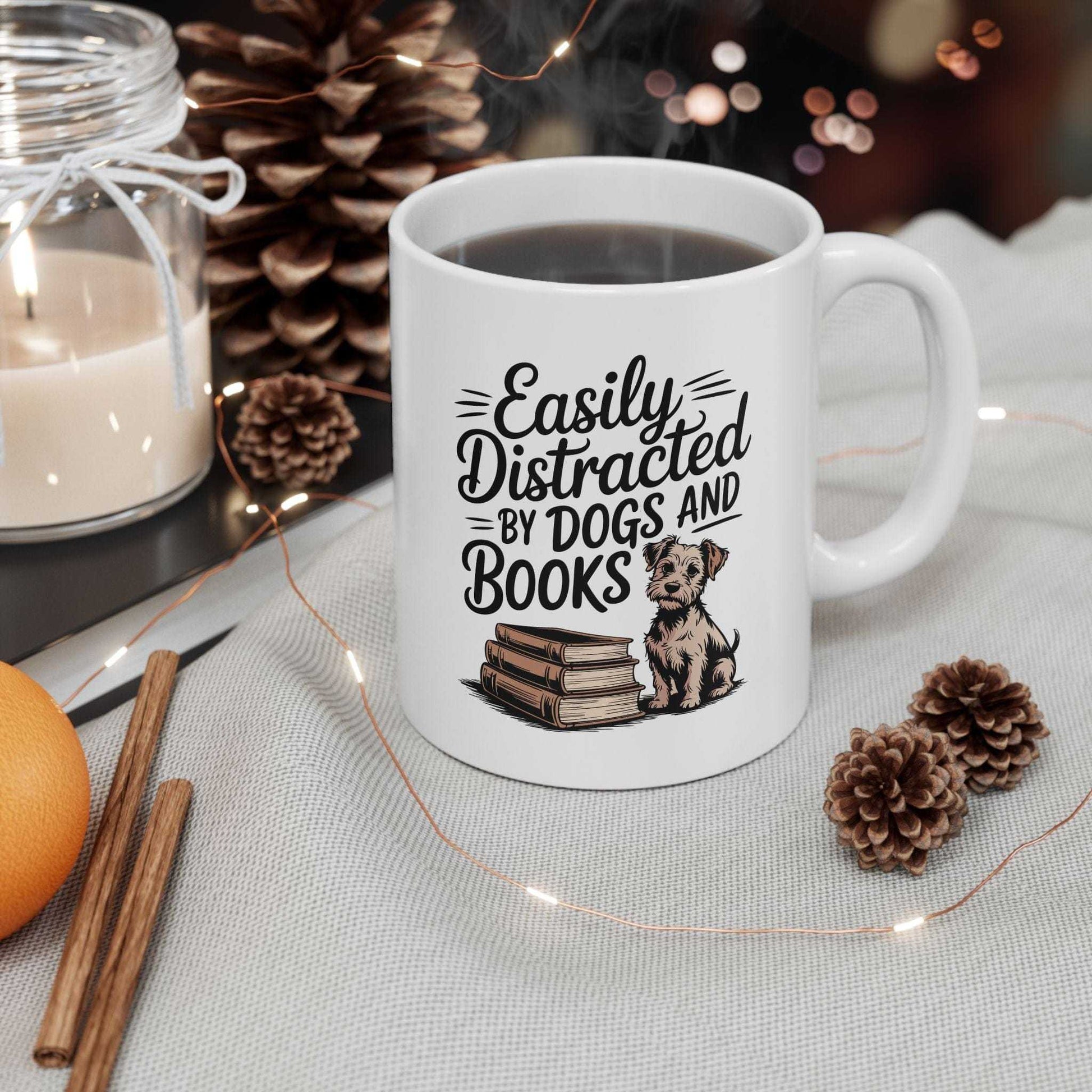 White mug with 'Easily Distracted by Dogs and Books' text and a dog illustration, surrounded by decorative items on a table.