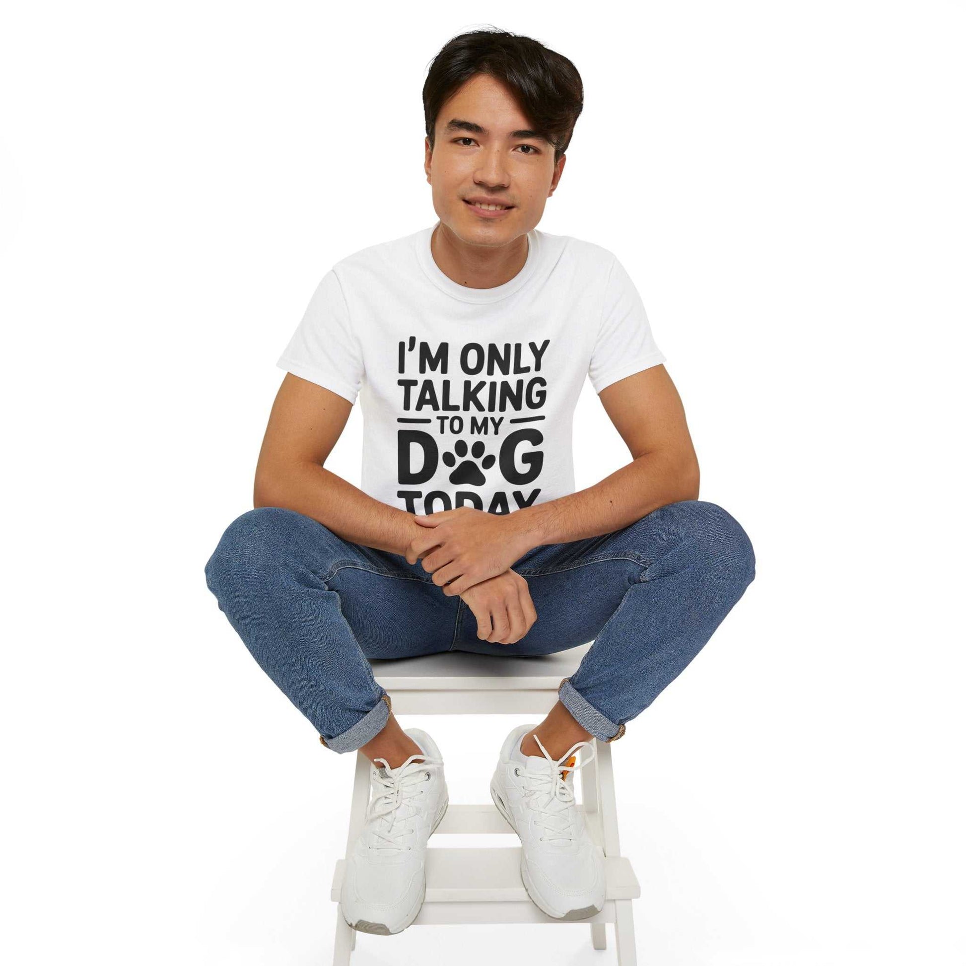 Person wearing a white t-shirt with text sitting on a white stool against a white background