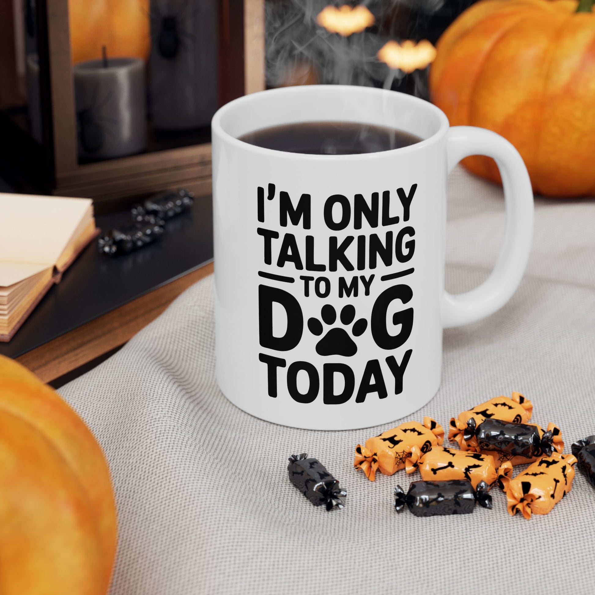 White mug with 'I'm only talking to my dog today' text, surrounded by Halloween-themed treats and pumpkins.