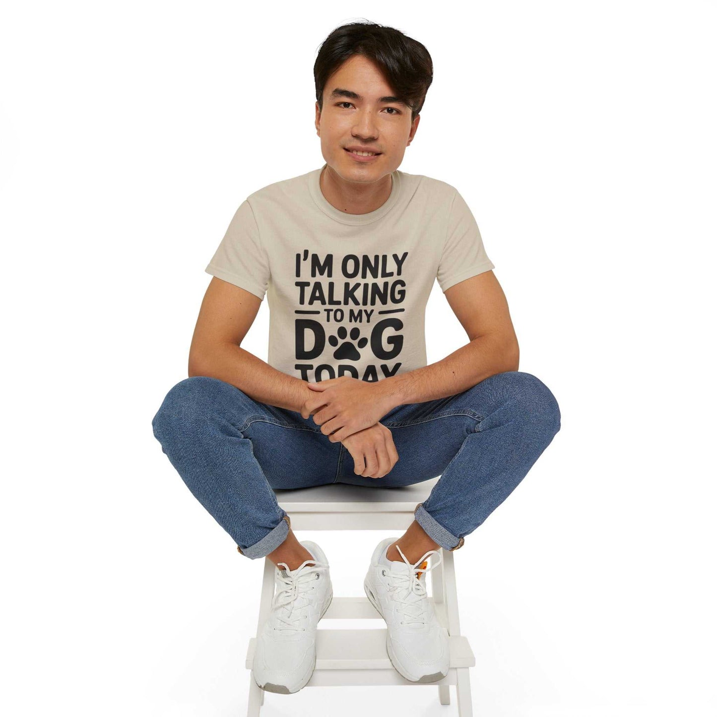 Person wearing a t-shirt with text sitting on a white stool against a white background