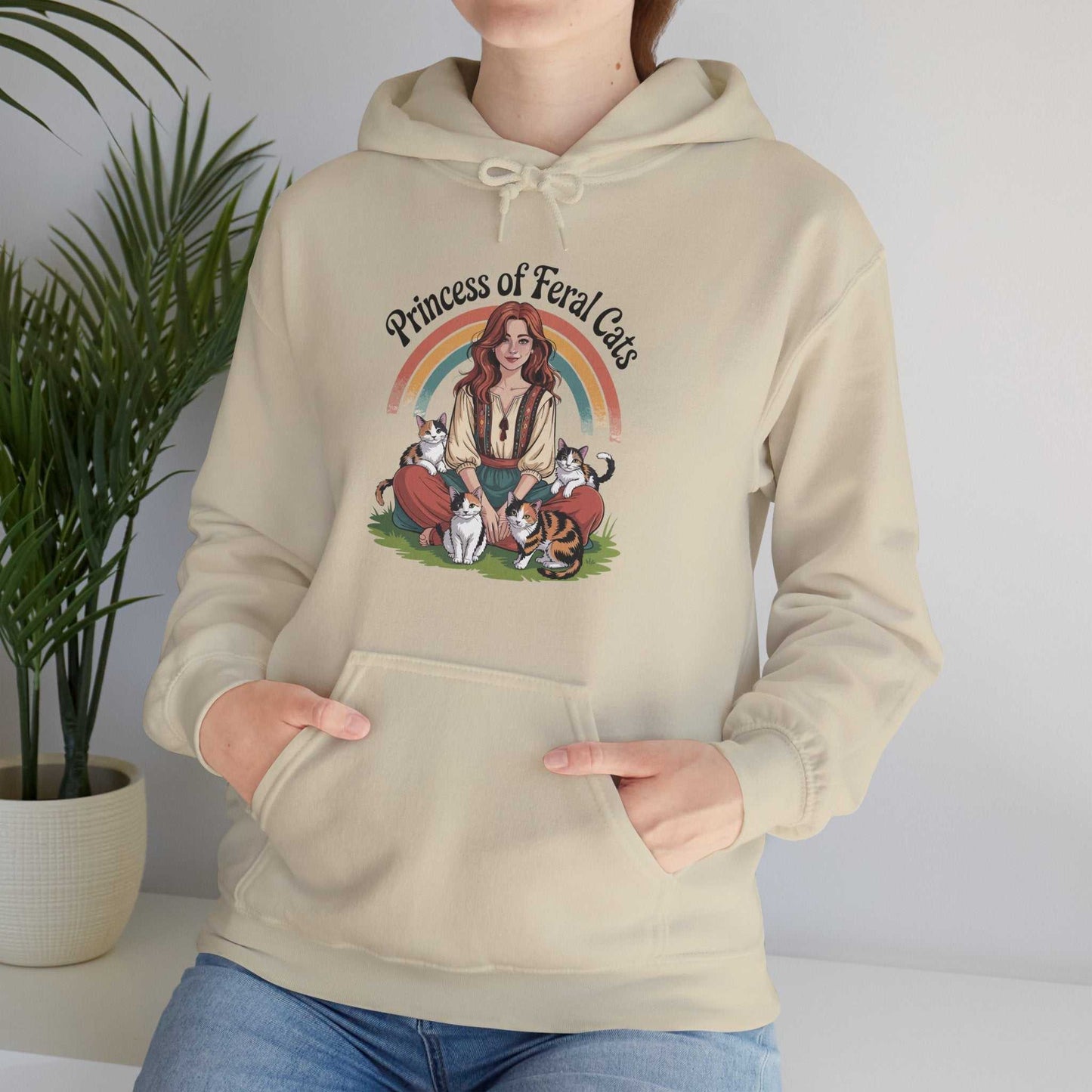 Beige hoodie with 'Princess of Feral Cats' design featuring a woman and cats, worn by a person.
