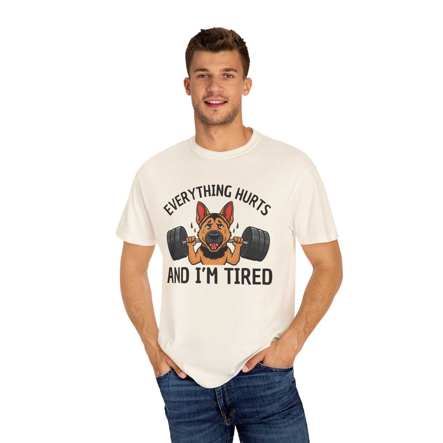Man wearing a white t-shirt with a graphic of a dog lifting weights and text 'Everything hurts and I'm tired' on a white background.
