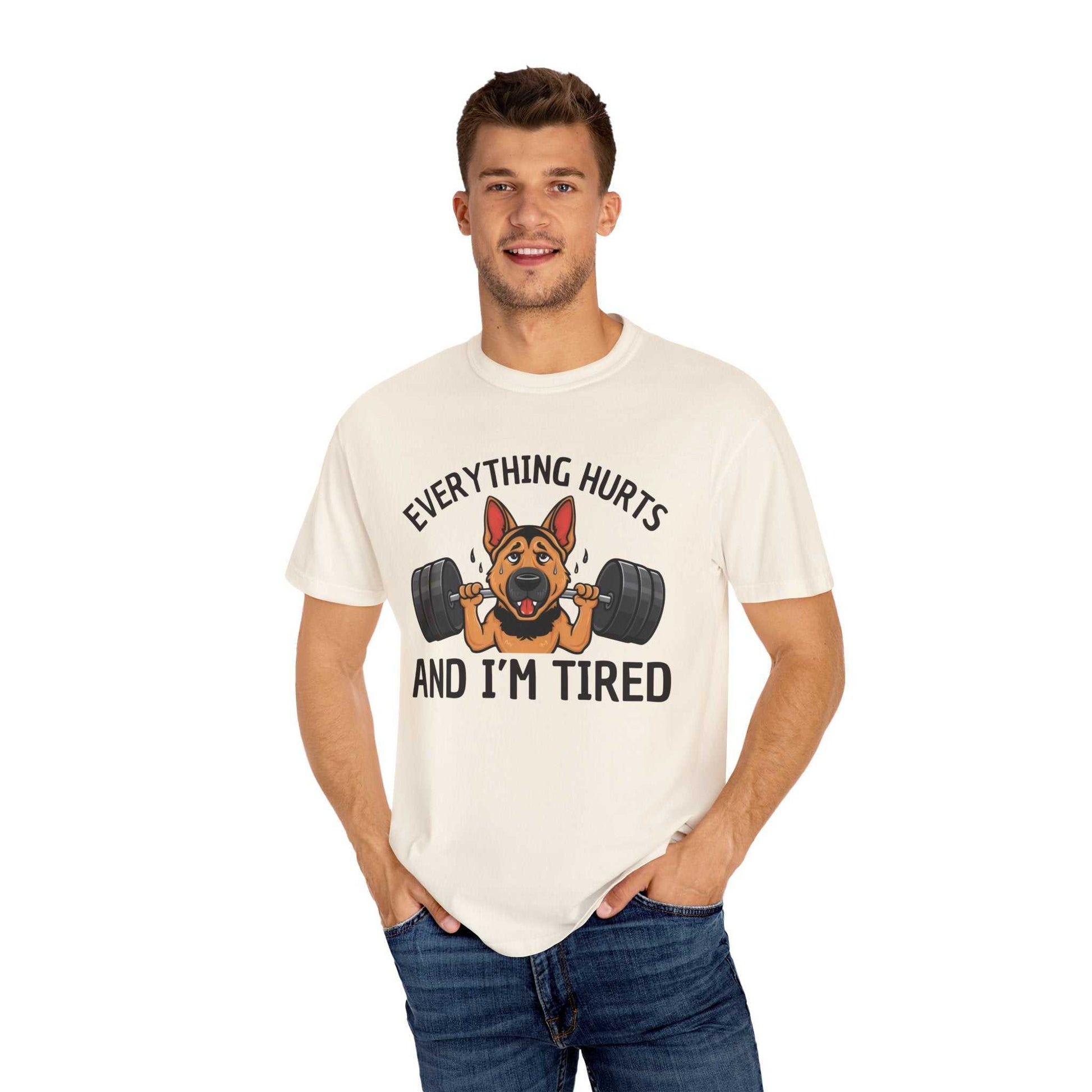 Man wearing a white t-shirt with a graphic of a dog lifting weights and text 'Everything hurts and I'm tired' on a white background.