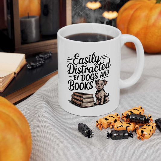 White mug with 'Easily Distracted by Dogs and Books' text and a dog illustration, surrounded by Halloween-themed treats and pumpkins.