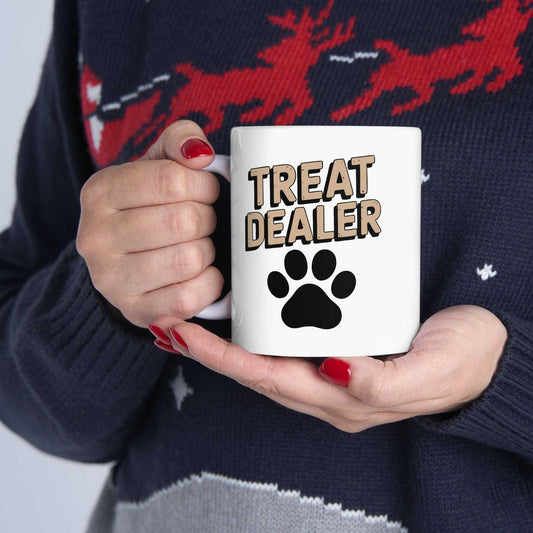 Person holding a mug with 'Treat Dealer' and a paw print design, wearing a festive sweater.