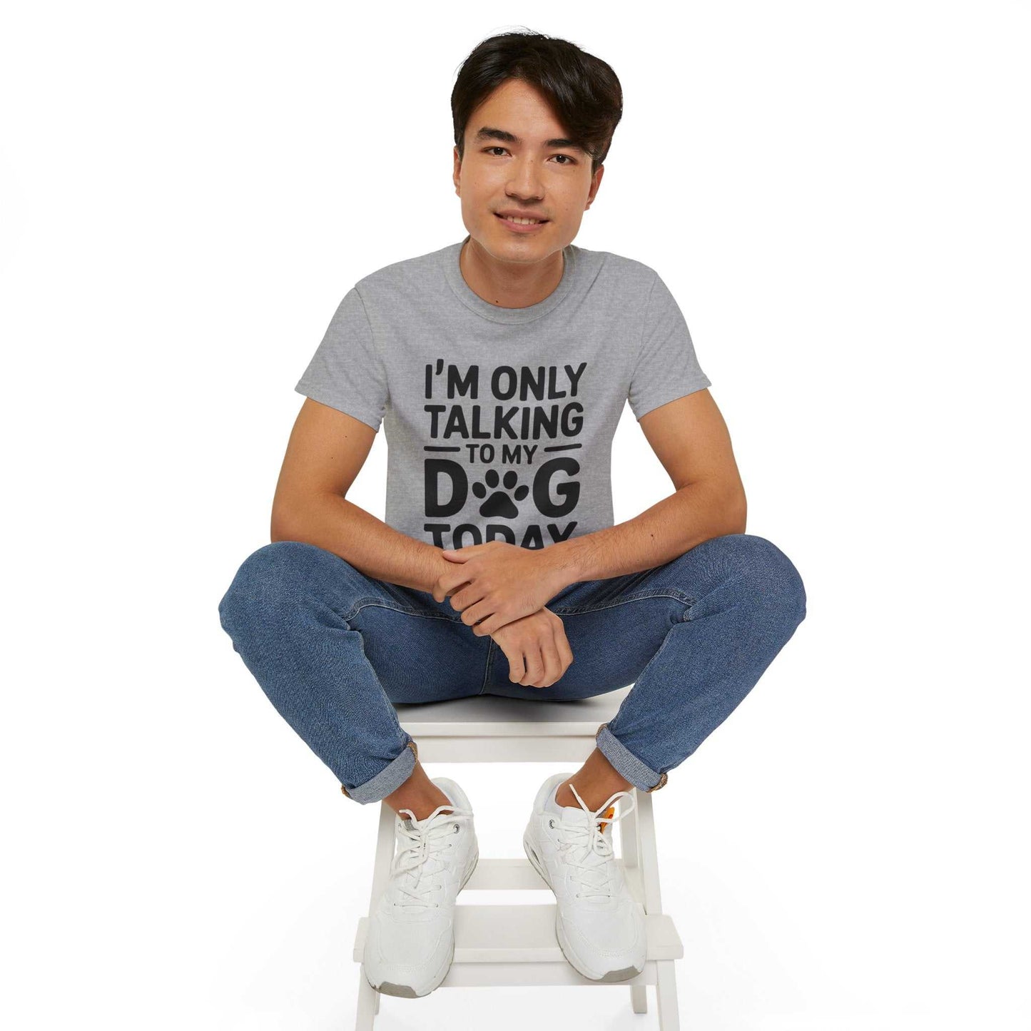 Person wearing a gray t-shirt with text sitting on a white stool against a white background