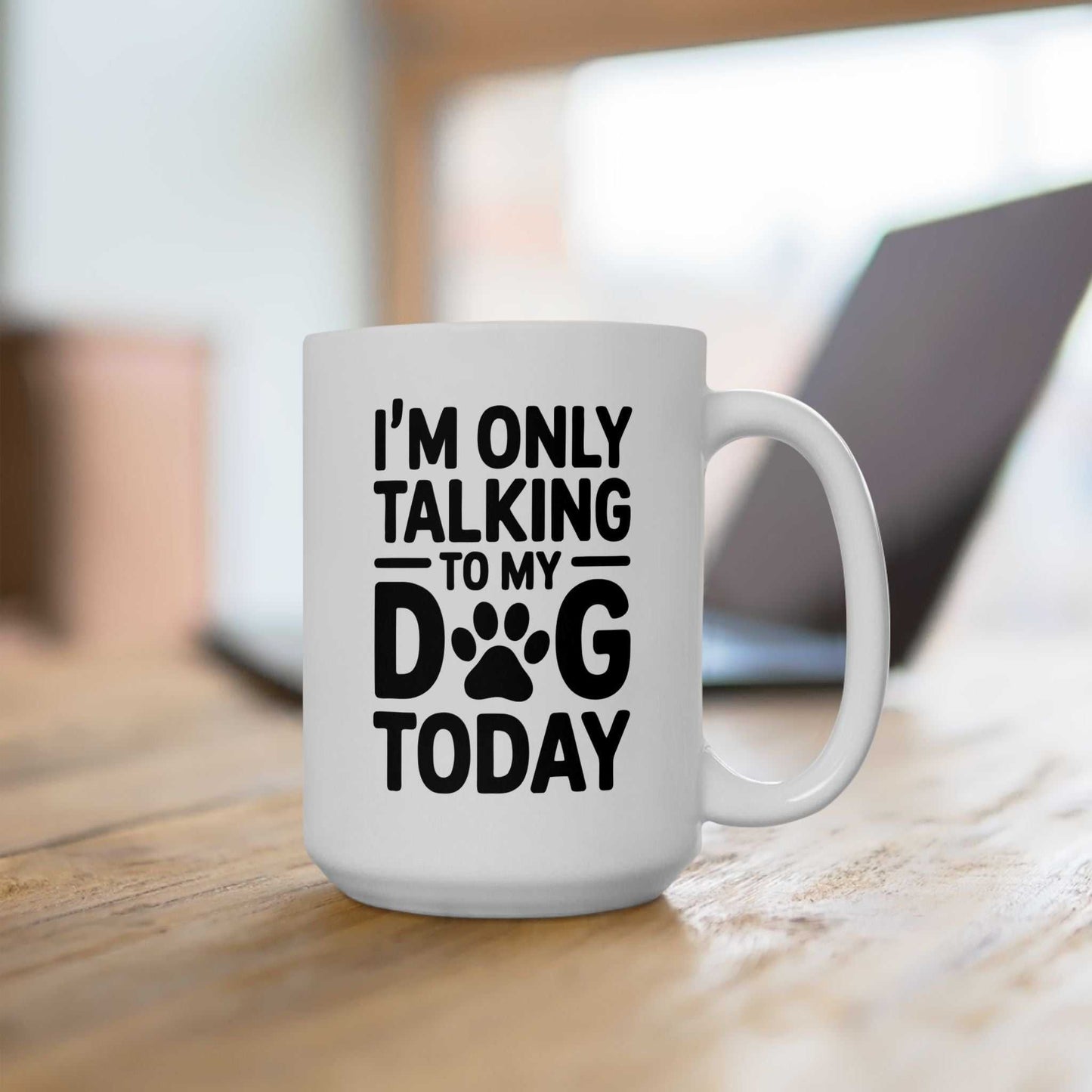 White mug with black text 'I'm only talking to my dog today' on a wooden surface.