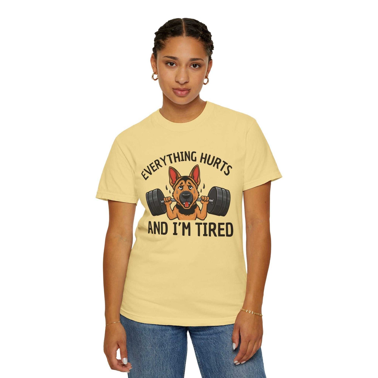 Person wearing a yellow t-shirt with a graphic of a dog lifting weights and text 'EVERYTHING HURTS AND I'M TIRED' on a white background.