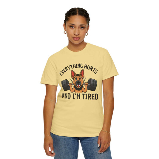 Person wearing a yellow t-shirt with a graphic of a dog lifting weights and text 'EVERYTHING HURTS AND I'M TIRED' on a white background.