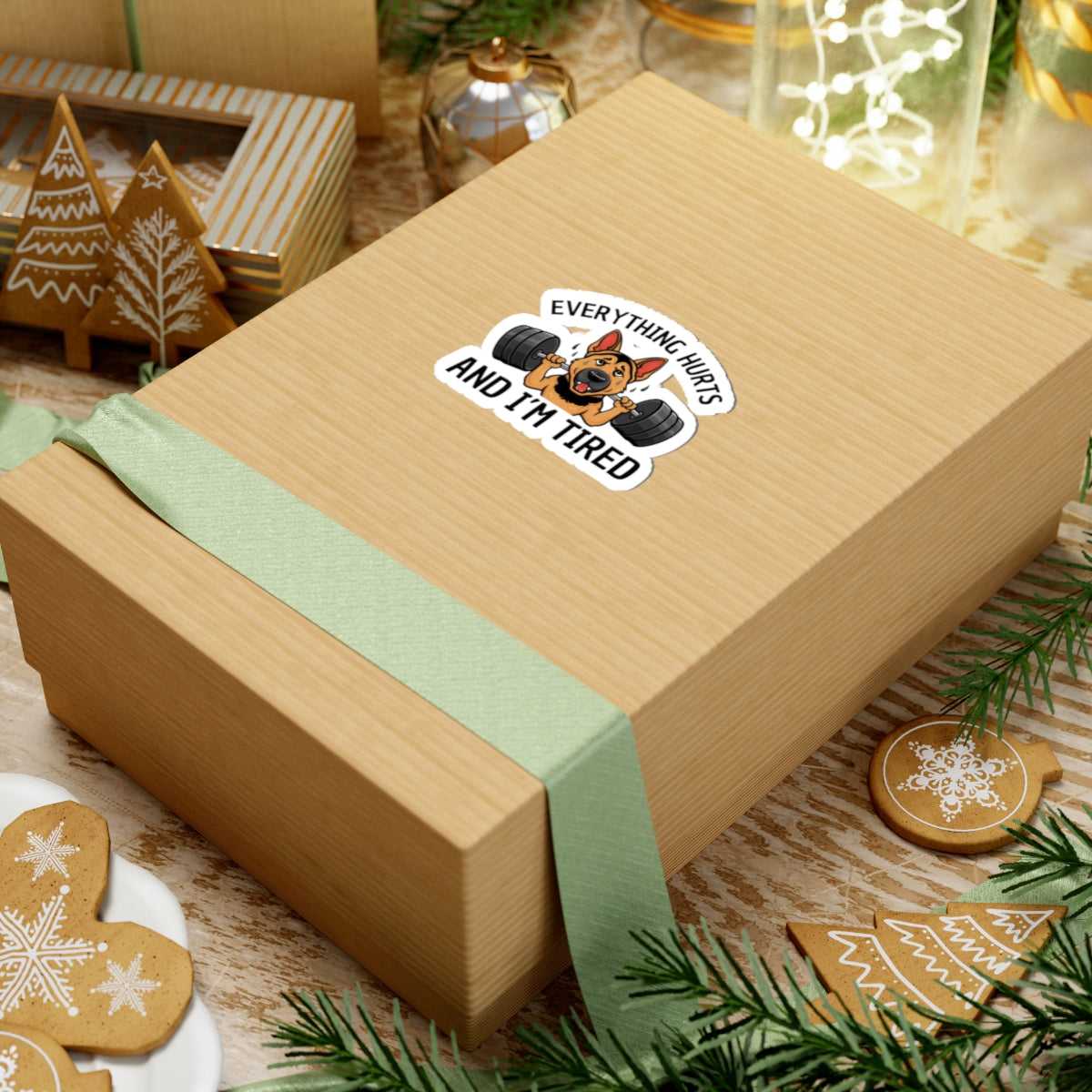 Gift box with a sticker and green ribbon on a festive background with cookies and decorations.