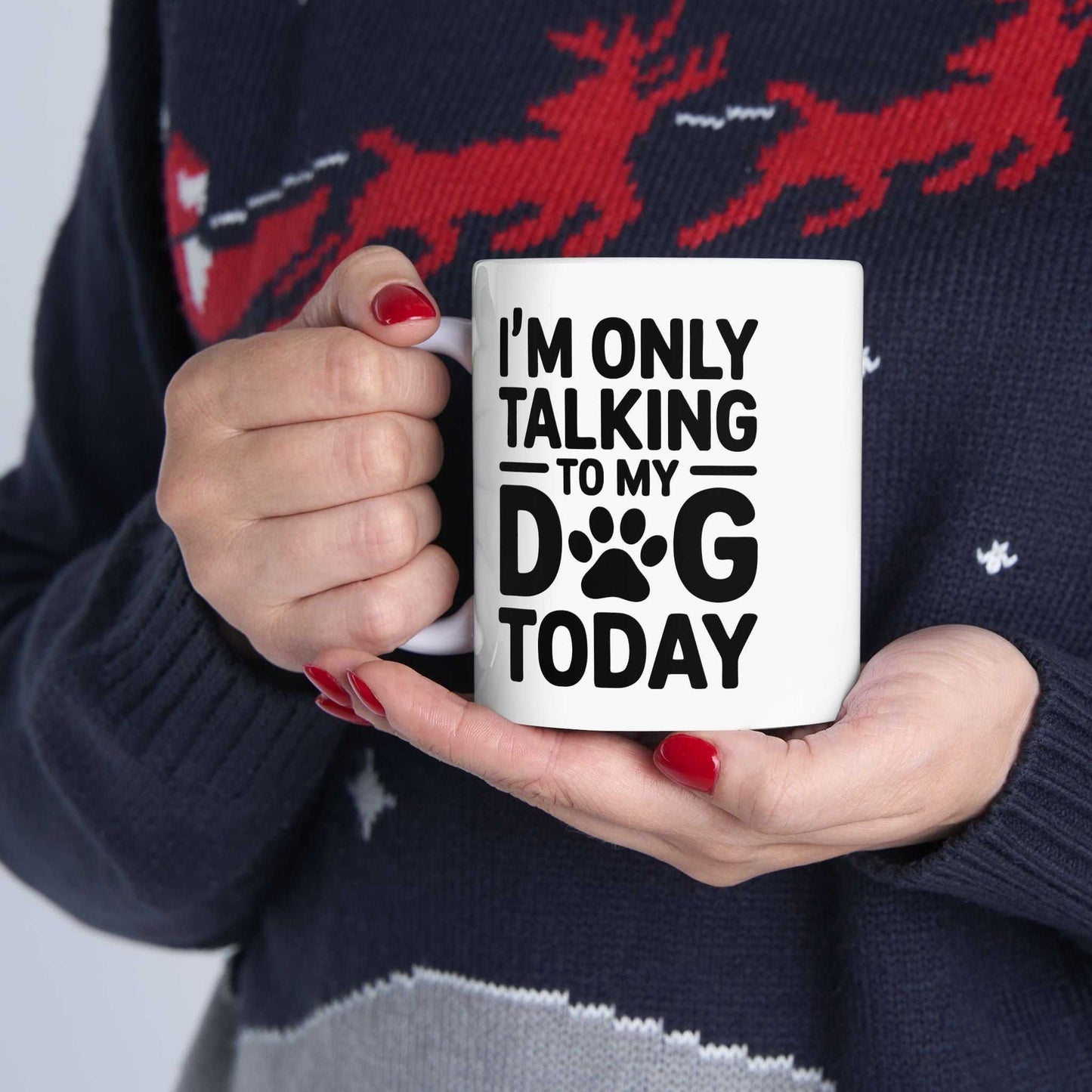 Person holding a mug with 'I'm only talking to my dog today' text, wearing a festive sweater.