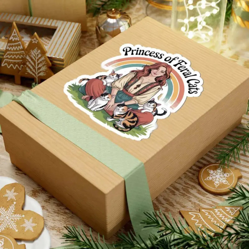 Wooden box with a decorative sticker featuring a woman and cats, set on a festive background with cookies and lights.